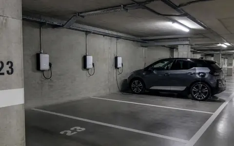 Parking souterrain de résidence équipé de bornes murales, une voiture en charge