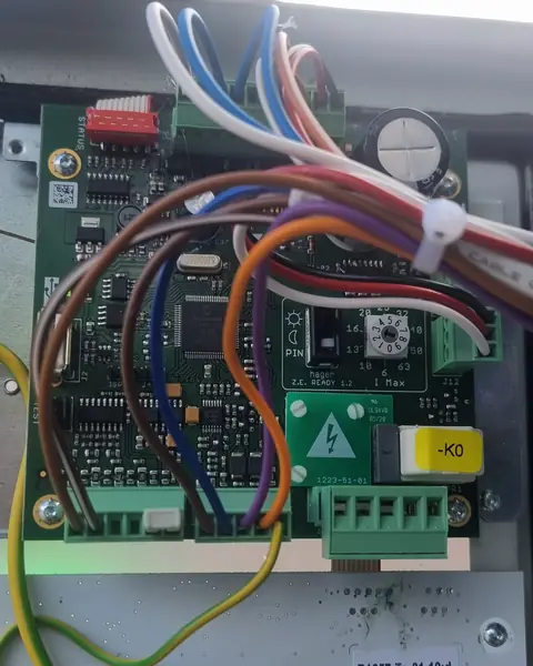 Carte électronique d’une borne de recharge Hager sur pied, ouverte pendant un dépannage