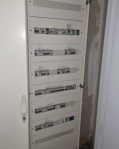 Armoire électrique ouverte avec des rangées de disjoncteurs étiquetés dans un local technique