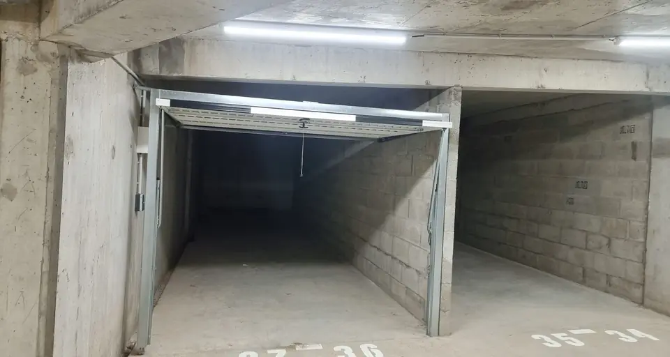 Parking souterrain en béton avec un box ouvert sous un éclairage au plafond
