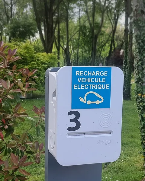 Borne de recharge sur pied numérotée 3, avec sa pastille de lecture de badge, devant une pelouse et des arbres