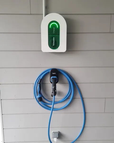 Borne Schneider Charge sur un bardage gris, câble de recharge bleu rangé sur son support